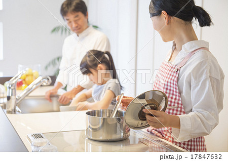 明るいキッチンで料理をする家族の写真素材