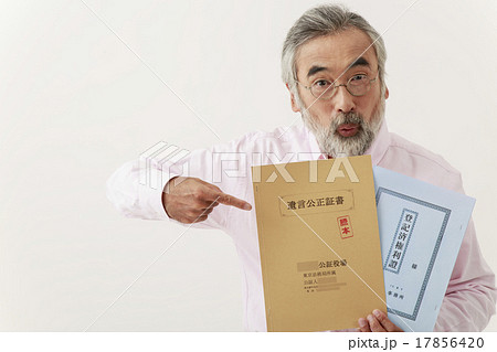 遺言公正証書と不動産登記簿を指差す男性シニア 17856420