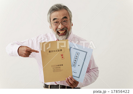 遺言公正証書と不動産登記簿を指差す男性シニア 17856422