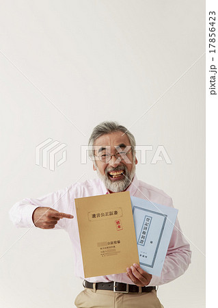 遺言公正証書と不動産登記簿を指差す男性シニア 17856423