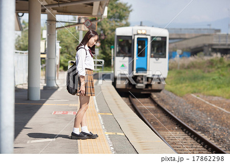 駅のホームで電車を待つ可愛らしい女子高生の写真素材