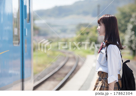 駅のホームで電車を待つ可愛らしい女子高生の写真素材