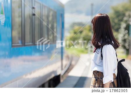 駅のホームで電車を待つ可愛らしい女子高生の写真素材