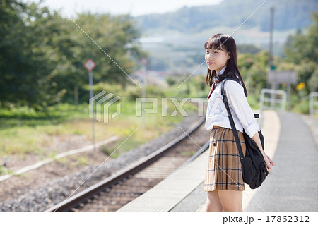 駅のホームで電車を待つ可愛らしい女子高生の写真素材