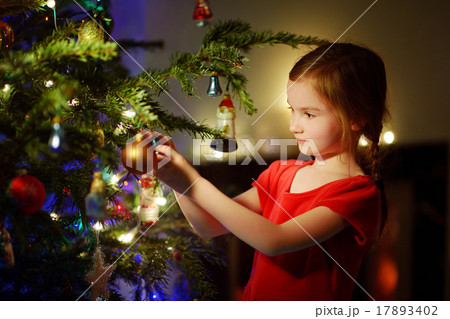 Adorable little girl decorating a Christmas tree Adorable little girl decorating a Christmas tree 17893402