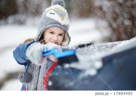 Adorable little girl helping to brush a snow 17893405