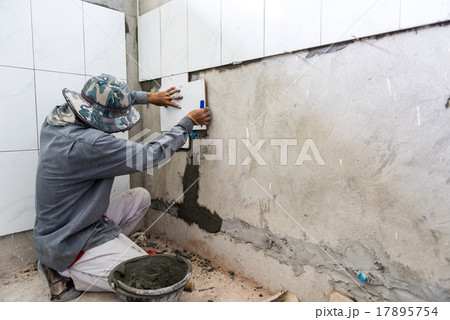 Ceramist puts tile on the wall.  17895754