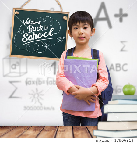 Composite image of cute pupil looking at camera holding notepad Composite image of cute pupil looking at camera holding notepad 17906313