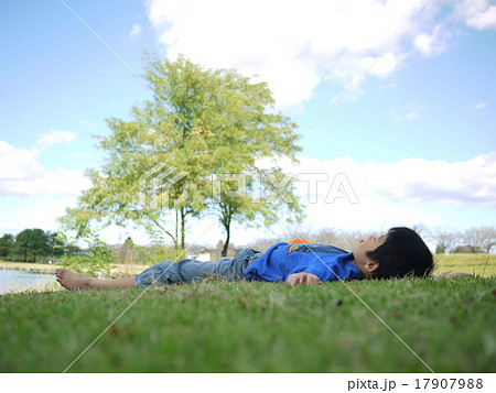 寝転んで空を見上げる男の子の写真素材