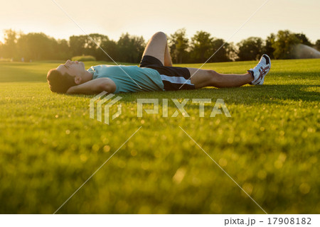 Guy lying in the park at sunset. 17908182