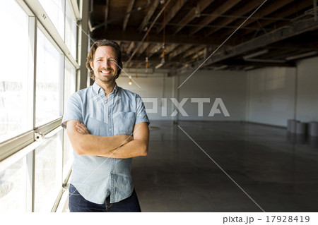 Man standing by window in warehouse 17928419
