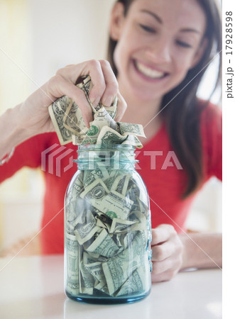 Woman putting money into jar 17928598