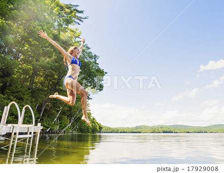 Young woman jumping into lake from jetty 17929008