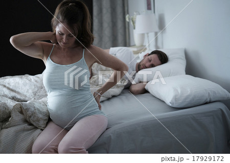 Woman sitting on bed and stretching stiff neck 17929172