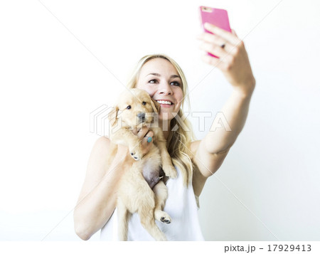 Studio shot of woman photographing self with Golden Retriever puppy Studio shot of woman photographing self with Golden Retriever puppy 17929413