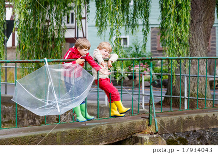 Two little kid boys with big umbrella outdoors Two little kid boys with big umbrella outdoors 17934043