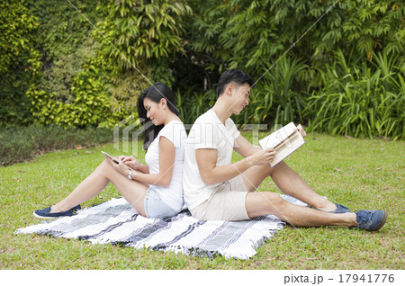 An Asian couple reading together in a park. An Asian couple reading together in a park. 17941776