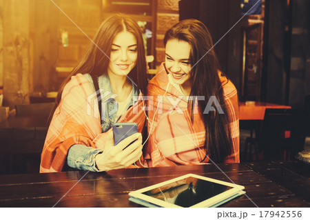 Two girl sitting listening to music with Two girl sitting listening to music with 17942556