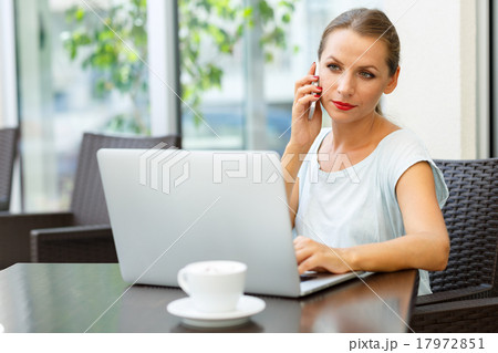 Attractive woman sitting in a cafe with a laptop and talking on Attractive woman sitting in a cafe with a laptop and talking on 17972851