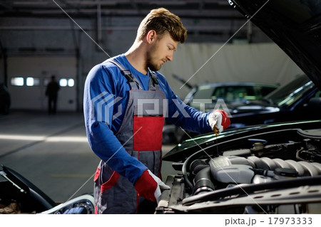 Mechanic checking oil level in a car workshop Mechanic checking oil level in a car workshop 17973333