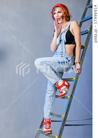 Girl mechanic with face art stands on ladder Girl mechanic with face art stands on ladder 17996914