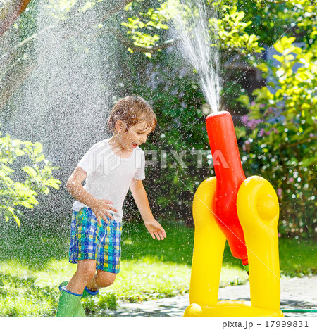 little kid boy playing  with a garden hose and water 17999831