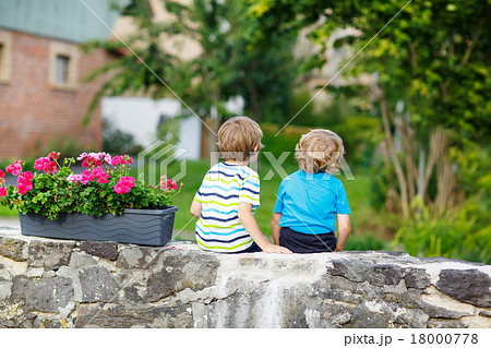 Two little kid boys sitting together on  bridge Two little kid boys sitting together on  bridge 18000778