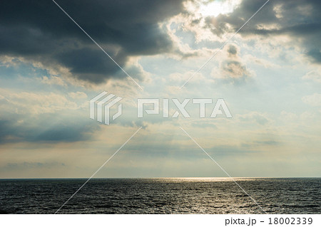 雲から光が差す空と海の写真素材