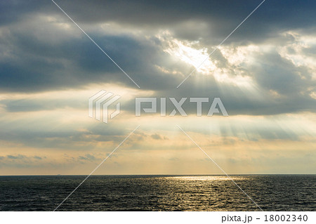 雲から光が差す空と海の写真素材