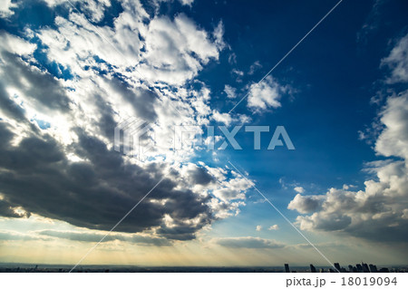 東京の都市風景 空 夕方 雲 空と雲と大都会 建造物 ビル群 日暮れ コピースペース 背景素材の写真素材