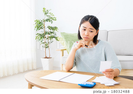 家計簿を書く女性　悩む女性　ショートカット　紙　領収書　レシート　コピースペース　リビング　室内 18032488