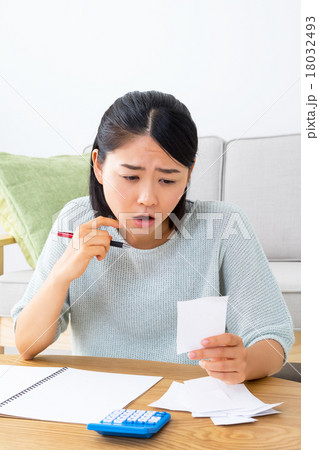 家計簿を書く女性　悩む女性　ショートカット　紙　領収書　レシート　コピースペース　リビング　室内 18032493