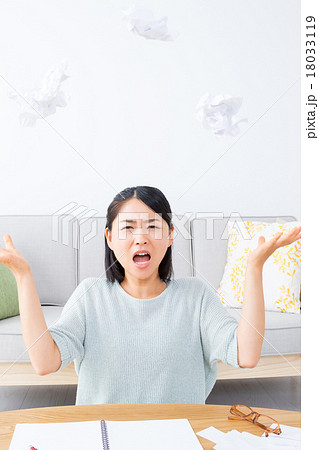 やけくその女性 執筆活動につかれた女性 紙を投げる ぐちゃぐちゃにした紙 うんざりした顔 女の人の写真素材