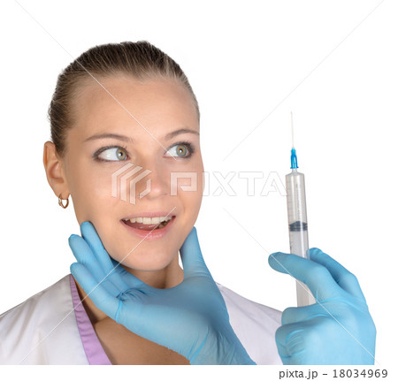 Surprised young woman looking at needle of syringe 18034969