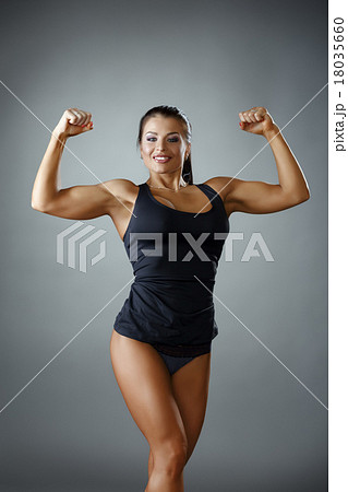 Happy female bodybuilder showing her biceps - Stock Photo