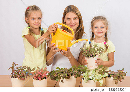 Mother and two daughters caring for potted flowers 18041304