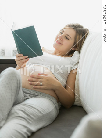 happy pregnant woman reading book on sofa happy pregnant woman reading book on sofa 18041881