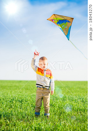 Young boy playing with his kite in a green field.  18043270