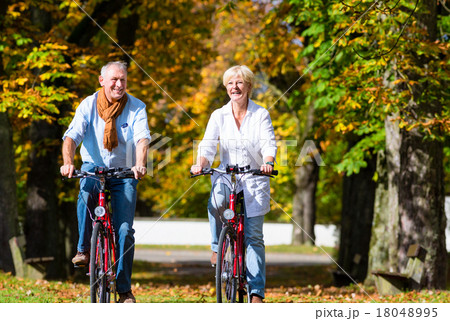 Seniors on bicycles having tour in park 18048995
