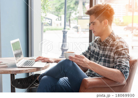 man drinking coffee with laptop on wooden table in coffee shop 18069930