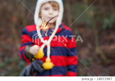 Little child in winter clothes holding burning sparkler 18072967
