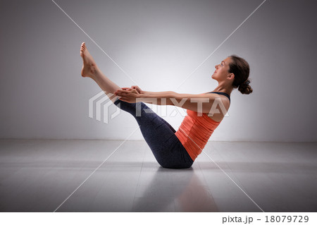 Woman practices yoga asana Paripurna navasana 18079729