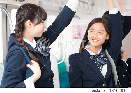 電車の中で会話をする中学生の女の子たちの写真素材