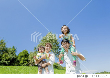 公園の緑の丘で遊ぶ4人家族 18110007