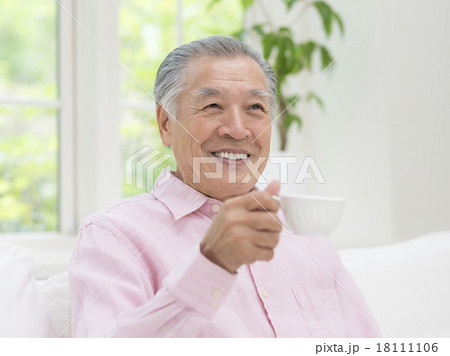 ティーカップを持つシニア男性の写真素材