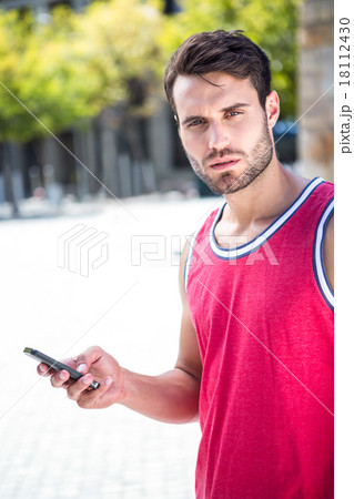 Handsome athlete sending a text 18112430