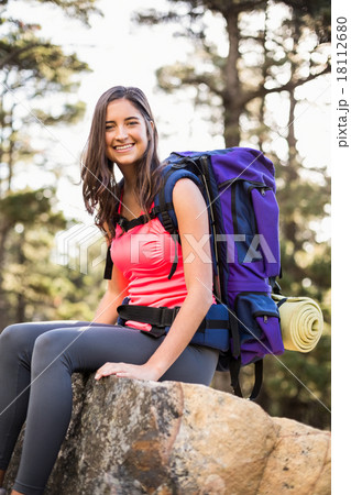 Young happy jogger sitting on rock and looking at camera 18112680