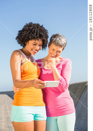 Two smiling sporty women looking at their selfies Two smiling sporty women looking at their selfies 18112808