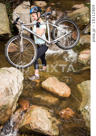 Profile view of a fit woman lifting her bike Profile view of a fit woman lifting her bike 18112809