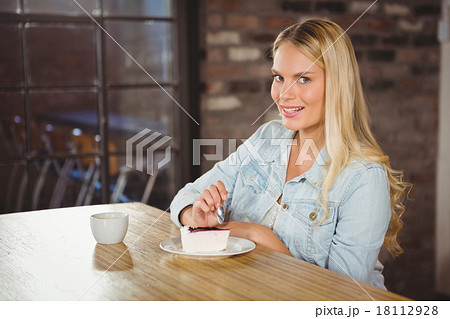 Smiling blonde eating cake and having coffee 18112928